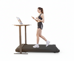Woman using a walking pad treadmill with a standing desk attached on a white background