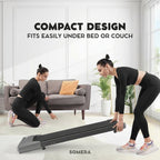 Two women in a living room with a compact exercise device, promoting its ease of storage.